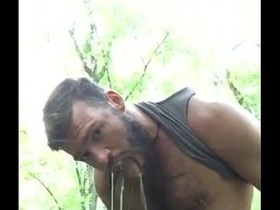 Hairy dude pissing on himself in the forest